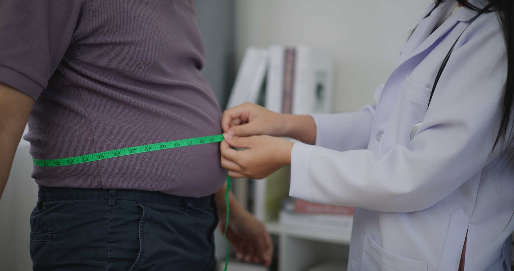 Un médico controla la cintura de un paciente para evaluar su obesidad.