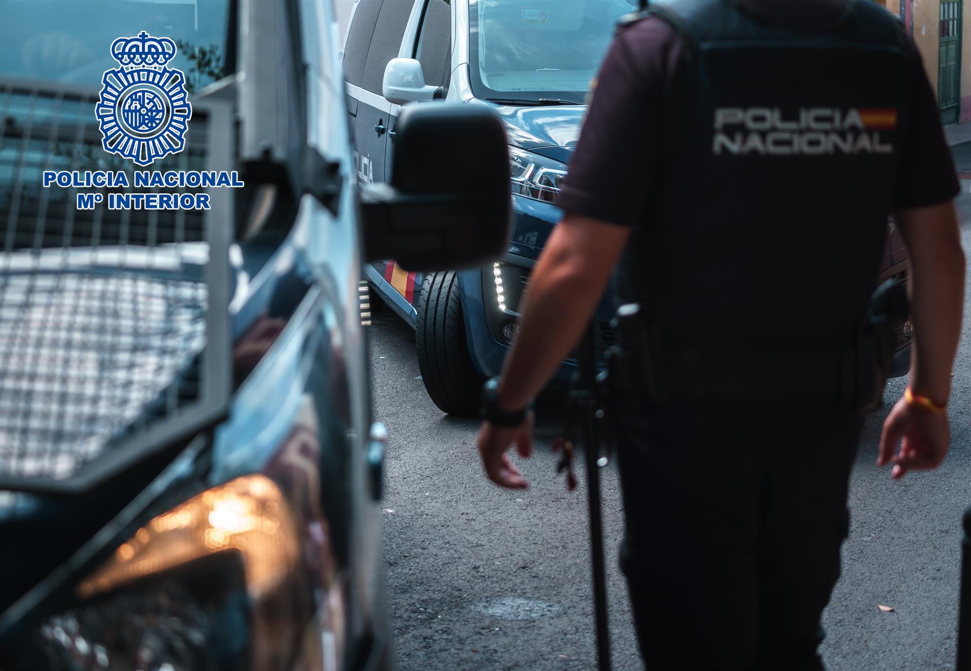 Un agente de la Policía Nacional junto a varios vehículos policiales.
