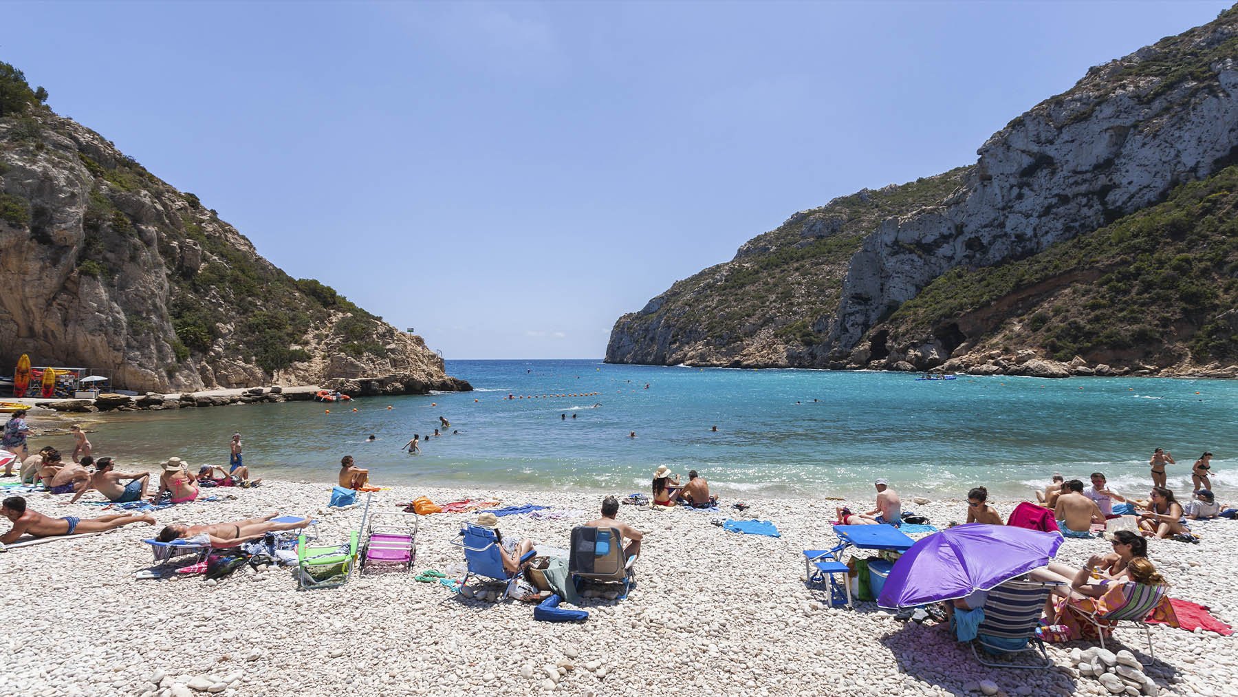 Personas disfrutando de la Cala de la Granadella. Foto: Diego Delso en Wikimedia Commons.