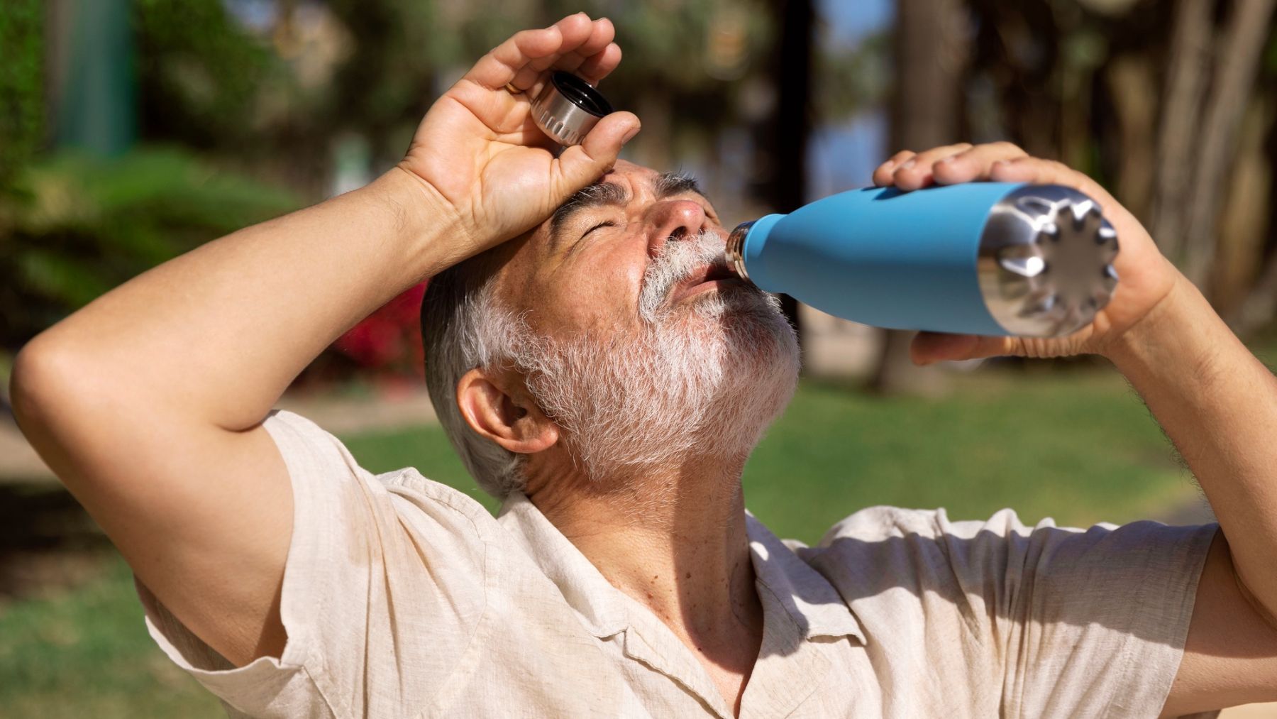 Una persona mayor bebiendo un refresco en su botella. Foto: Freepik