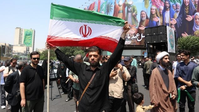 Un hombre iraní sostiene la bandera de Irán en Teherán tras los ataques este viernes. (EFE)
