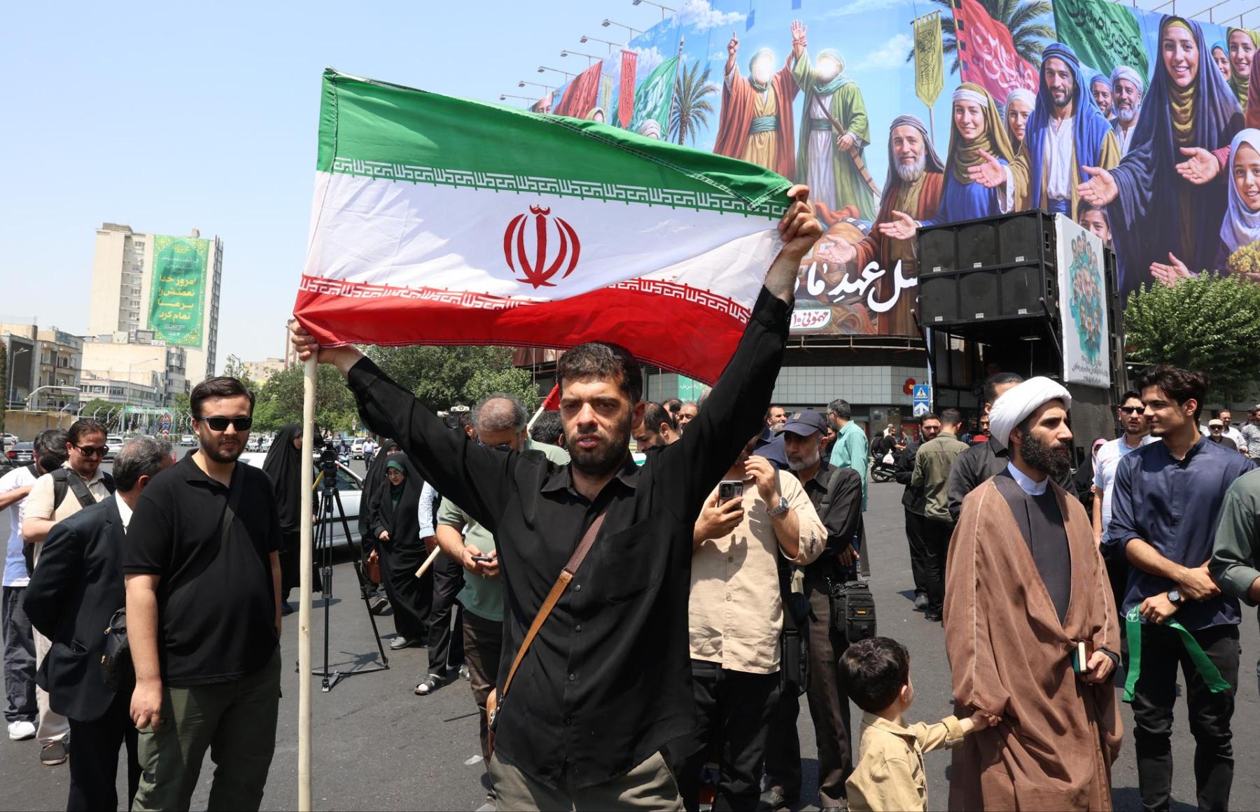 Un hombre iraní sostiene la bandera de Irán en Teherán tras los ataques este viernes. (EFE)