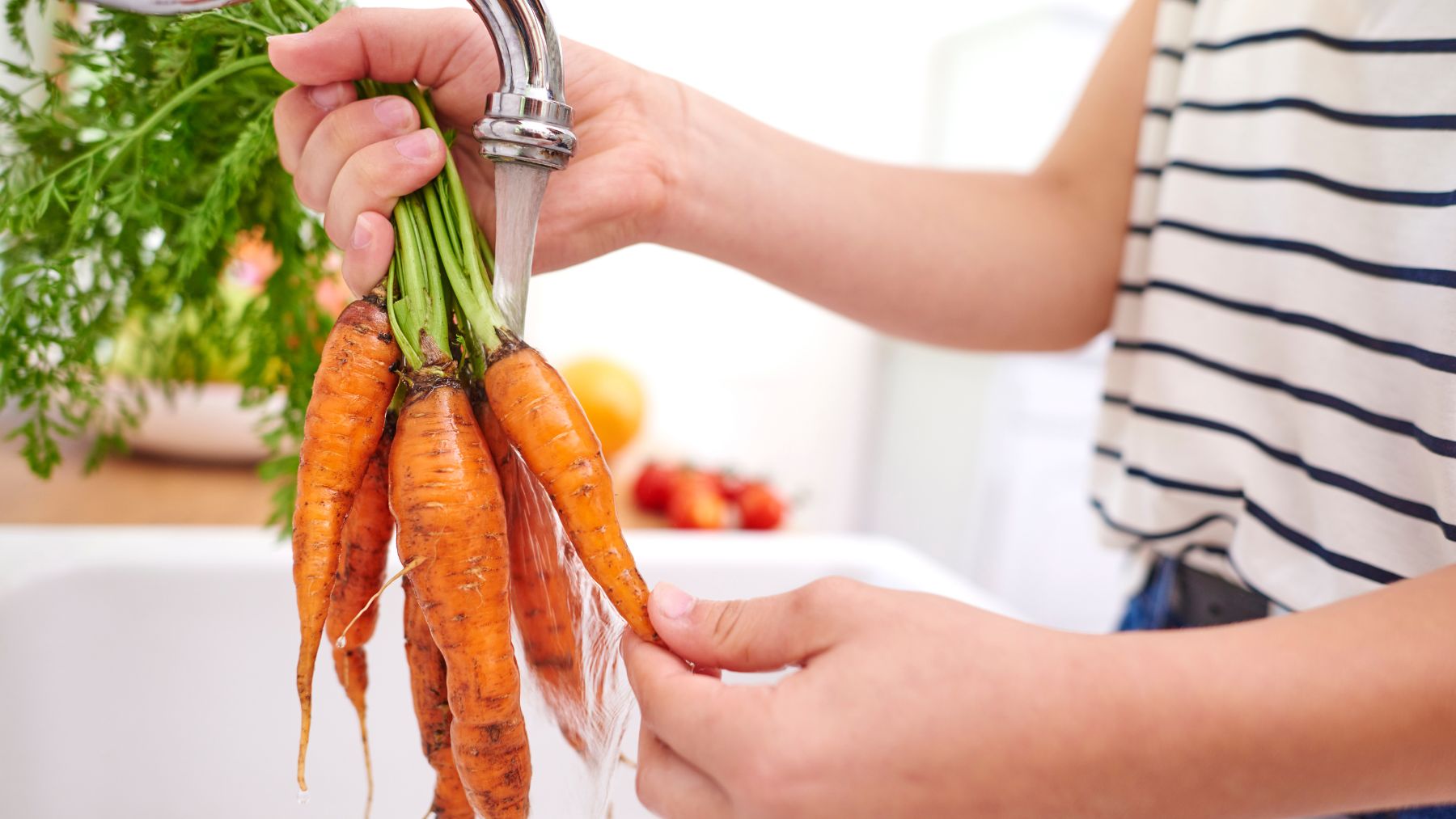 Una persona lavando zanahorias. Foto: Freepik