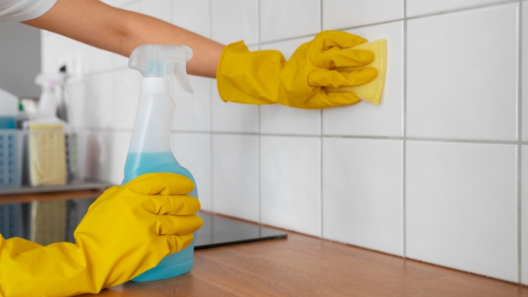 Una persona limpiando los azulejos de la cocina. Foto: Freepik