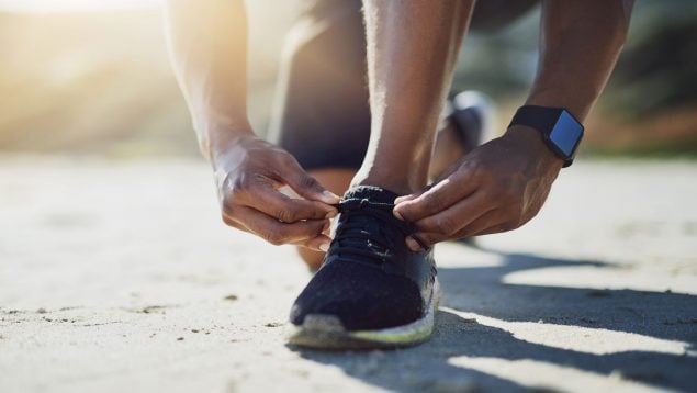 Un hombre se ata los cordones de las zapatillas.