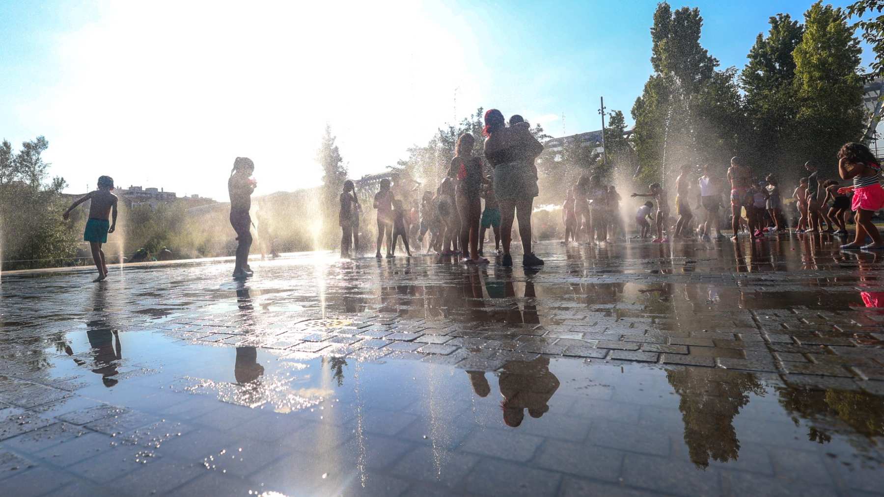 Varios niños se refrescan en una fuente.