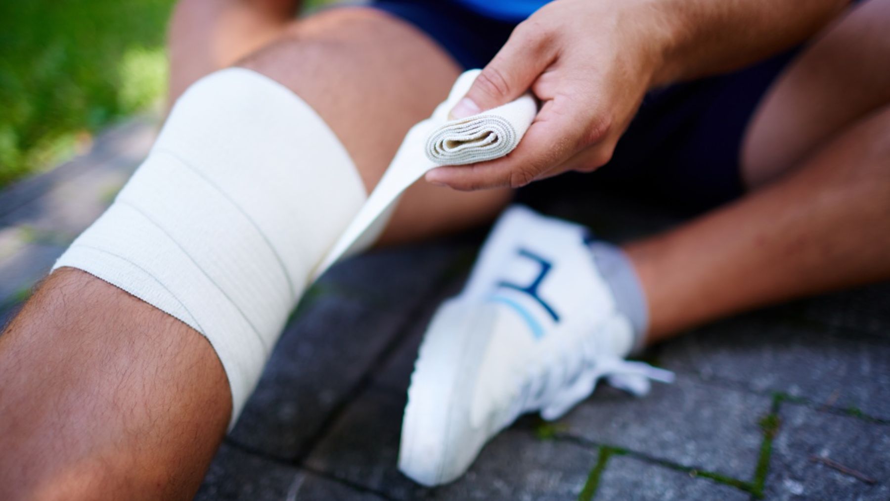 Un deportista revisa la venda de su rodilla.