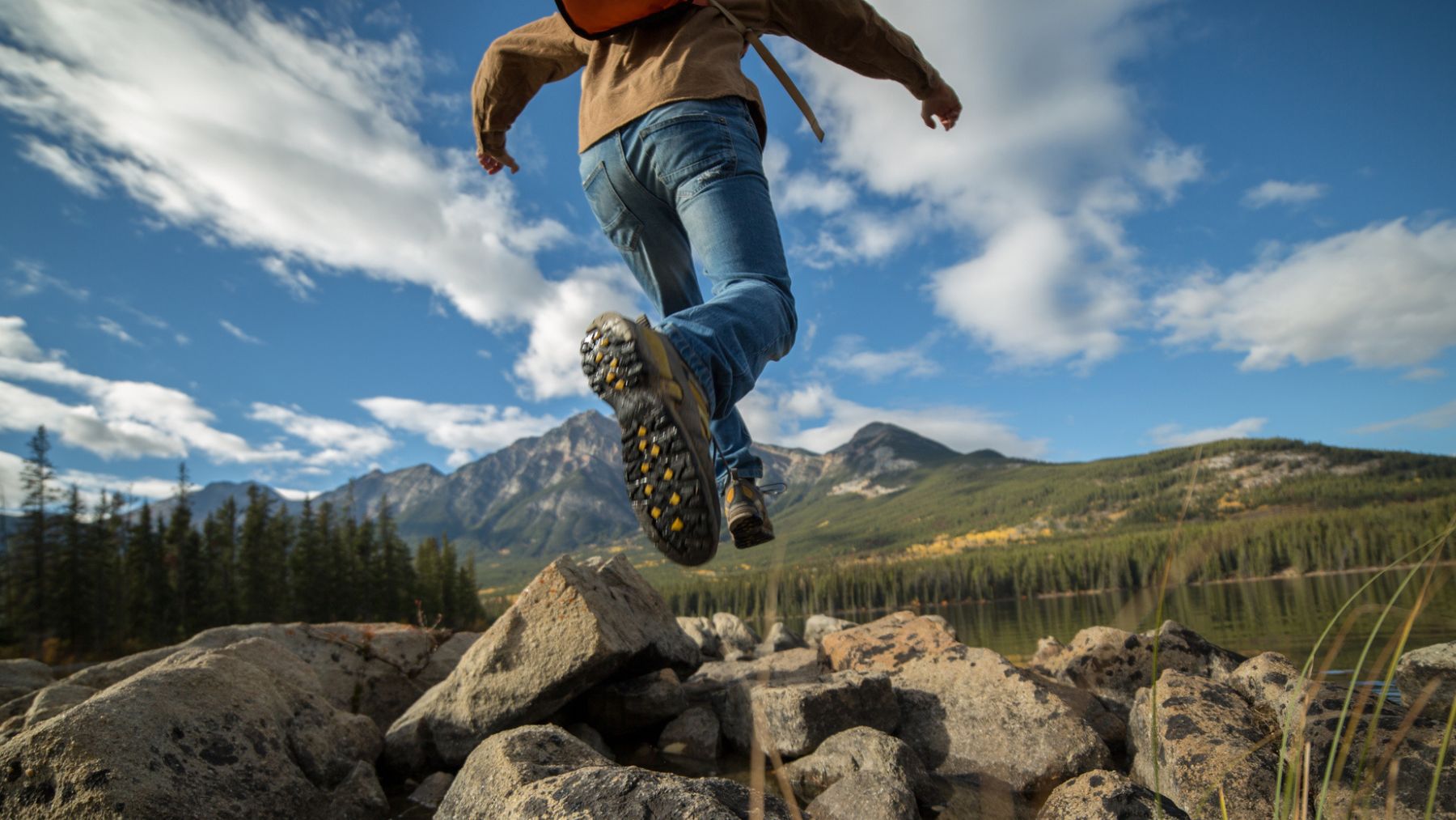 Un joven salta en la montaña.