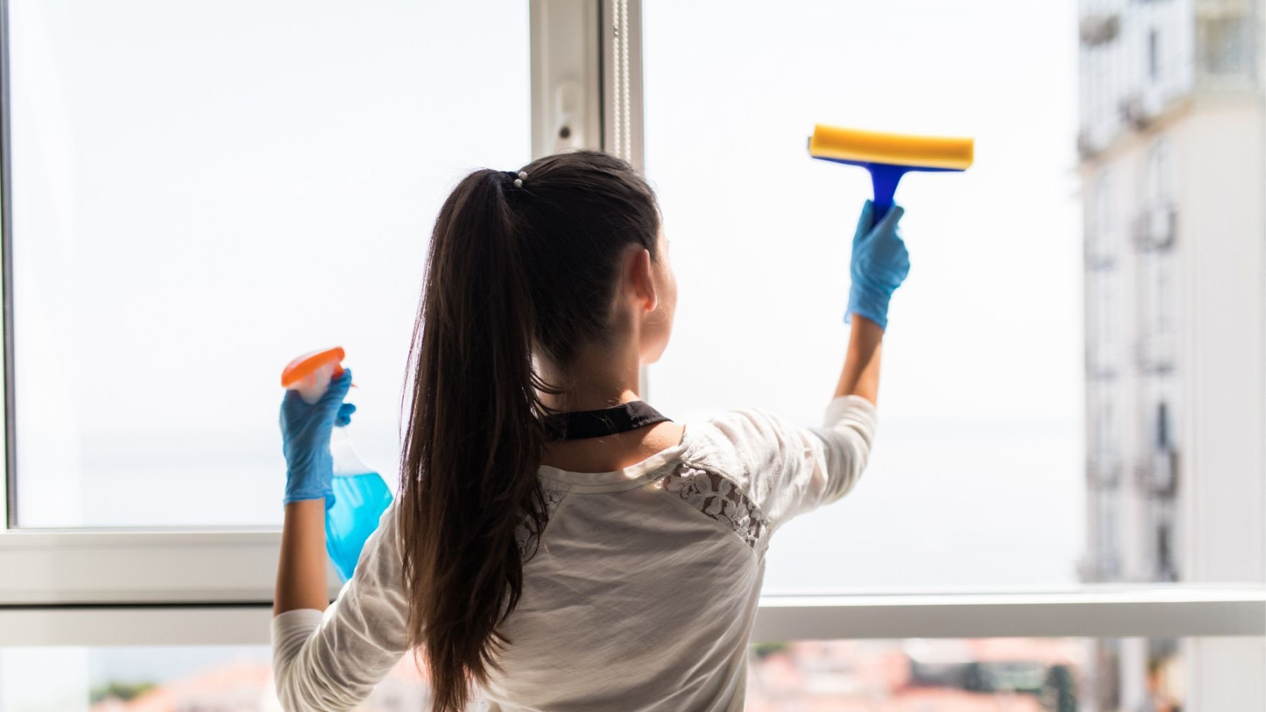 Una mujer limpiando los cristales. Foto: Freepik