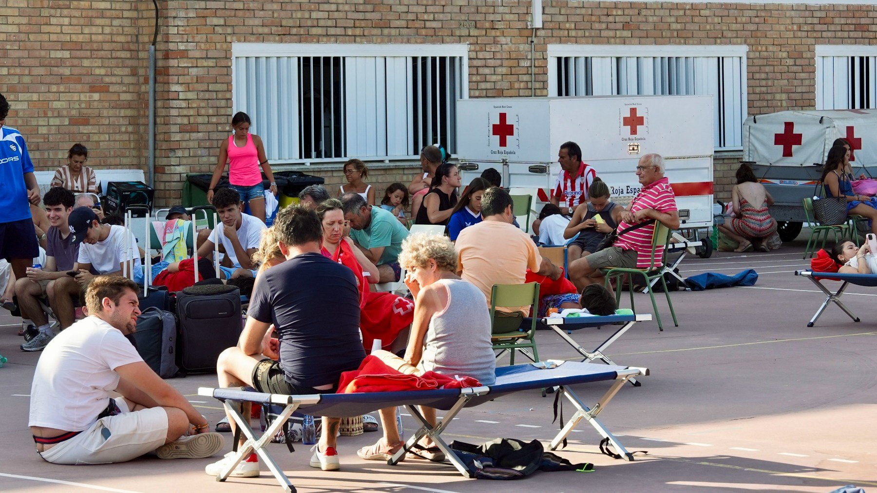 Turistas y vecinos de Atlanterra tras pasar la noche del lunes en un colegio por los desalojos. (Efe)