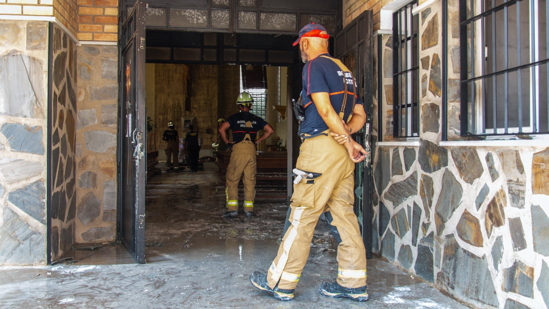 Un bombero frente a las puertas de la Iglesia de Santiago Apóstol de El Pozuelo, incendiada este domingo. (Efe)