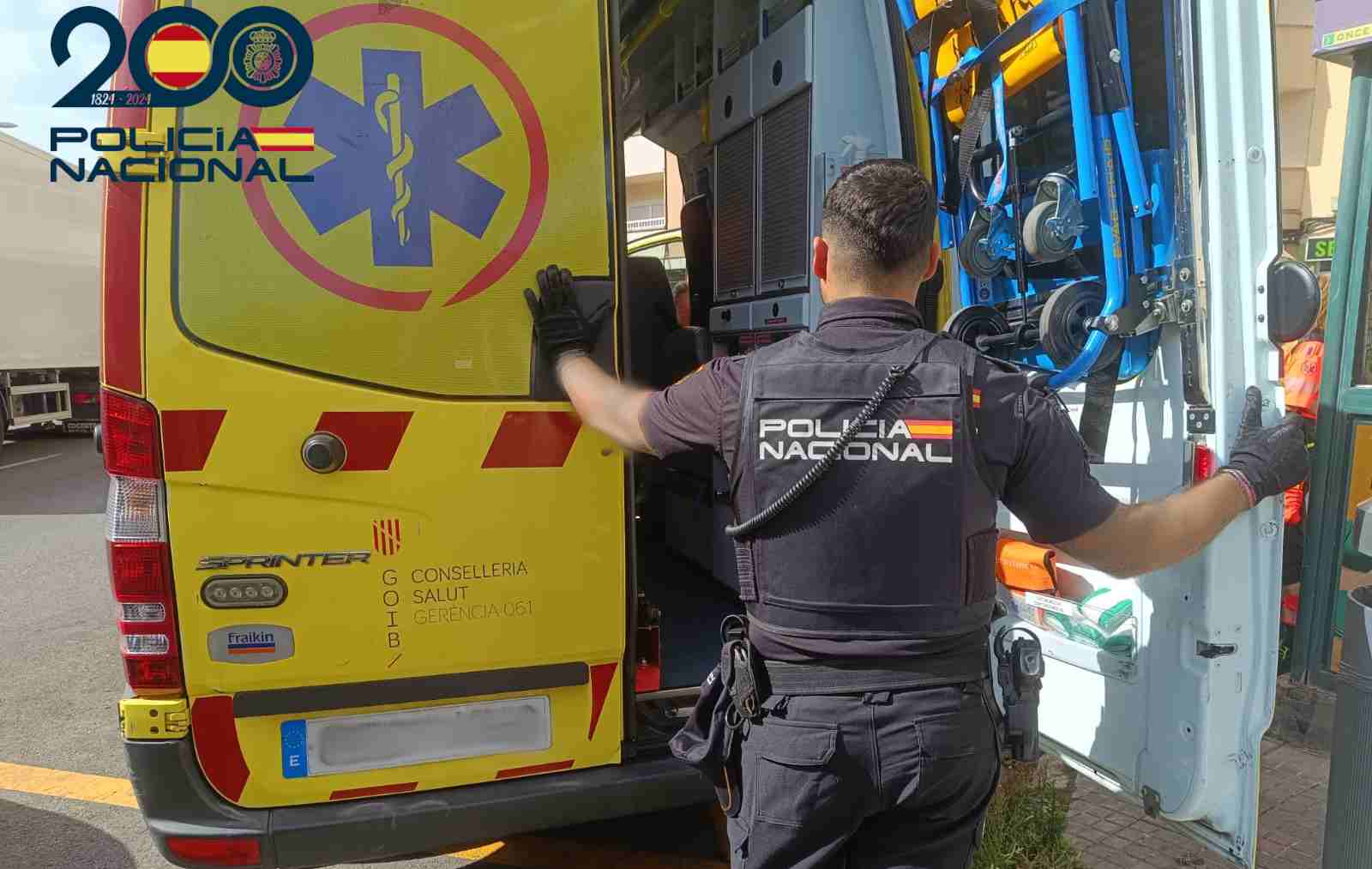 Un agente de la Policía Nacional junto a una ambulancia.