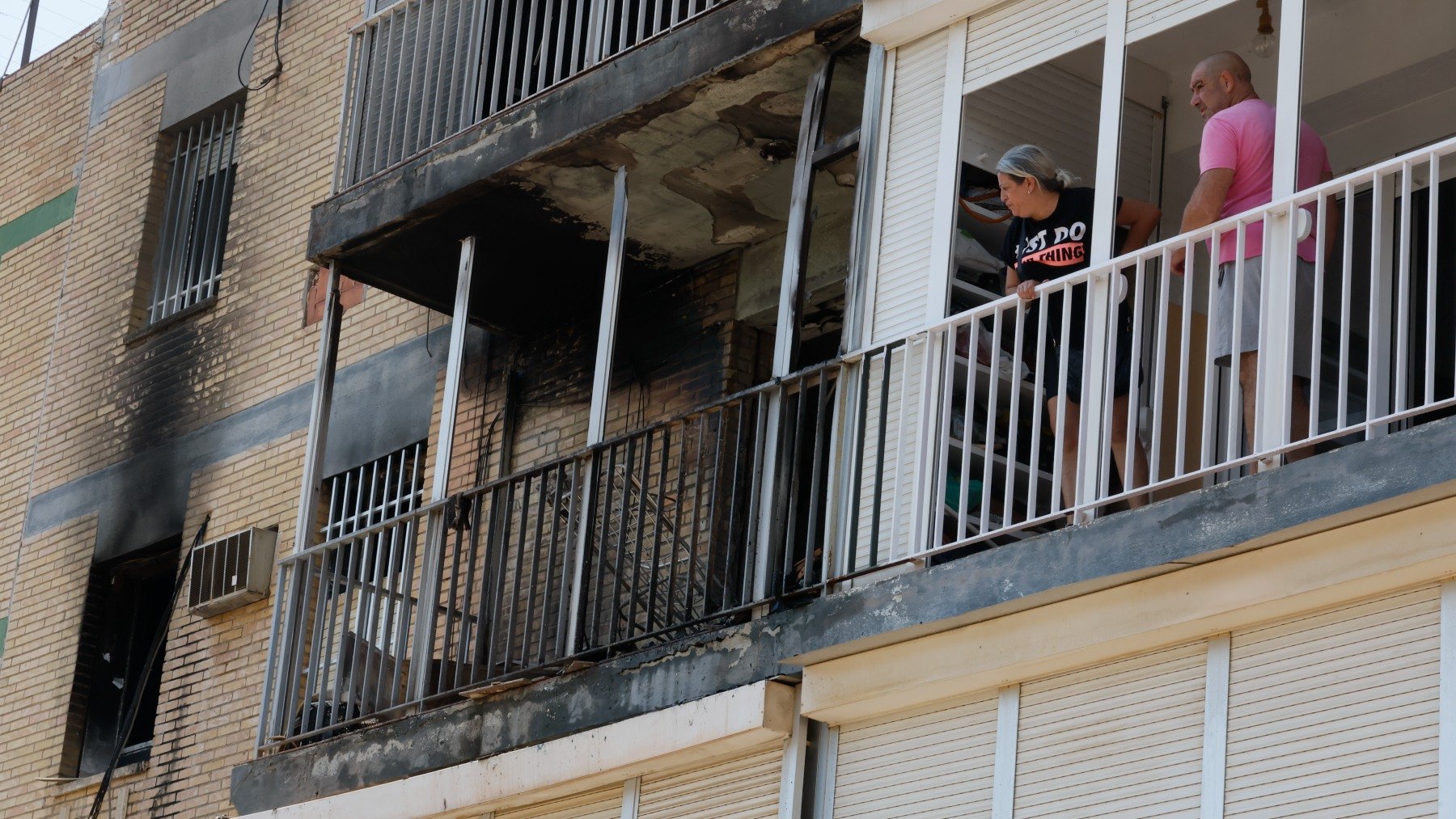 Vecinos observan la vivienda de Alcalá de Guadaíra calcinada tras el incendio. (Efe)