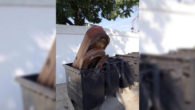 Un trabajador del cementerio tira un ataúd usado a un contenedor de basura en un pueblo de Sevilla