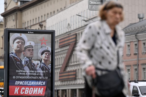 Una persona camina a lado de un cartel militar en Moscú. (Getty Images)