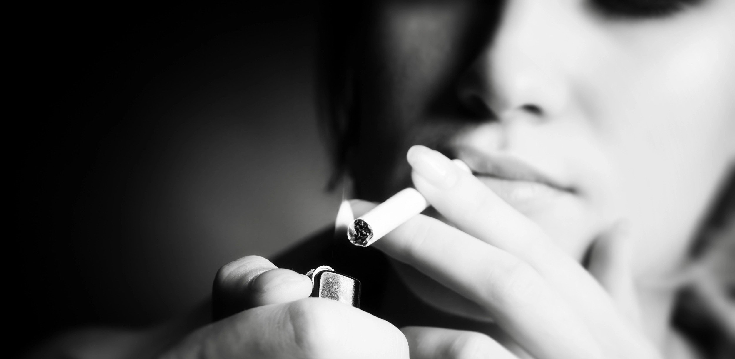 Una mujer prende un cigarrillo.