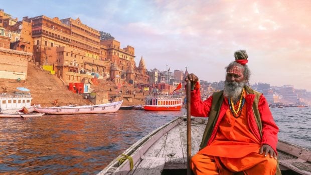 Un sadhu indio toma un paseo en barco por el río Ganges.