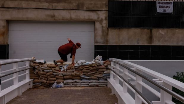 Un hombre salta sacos de arena, instalados para prevenir el desbordamiento del barranco de La Saleta en Aldaia, Valencia. (Foto: Europa/Press).