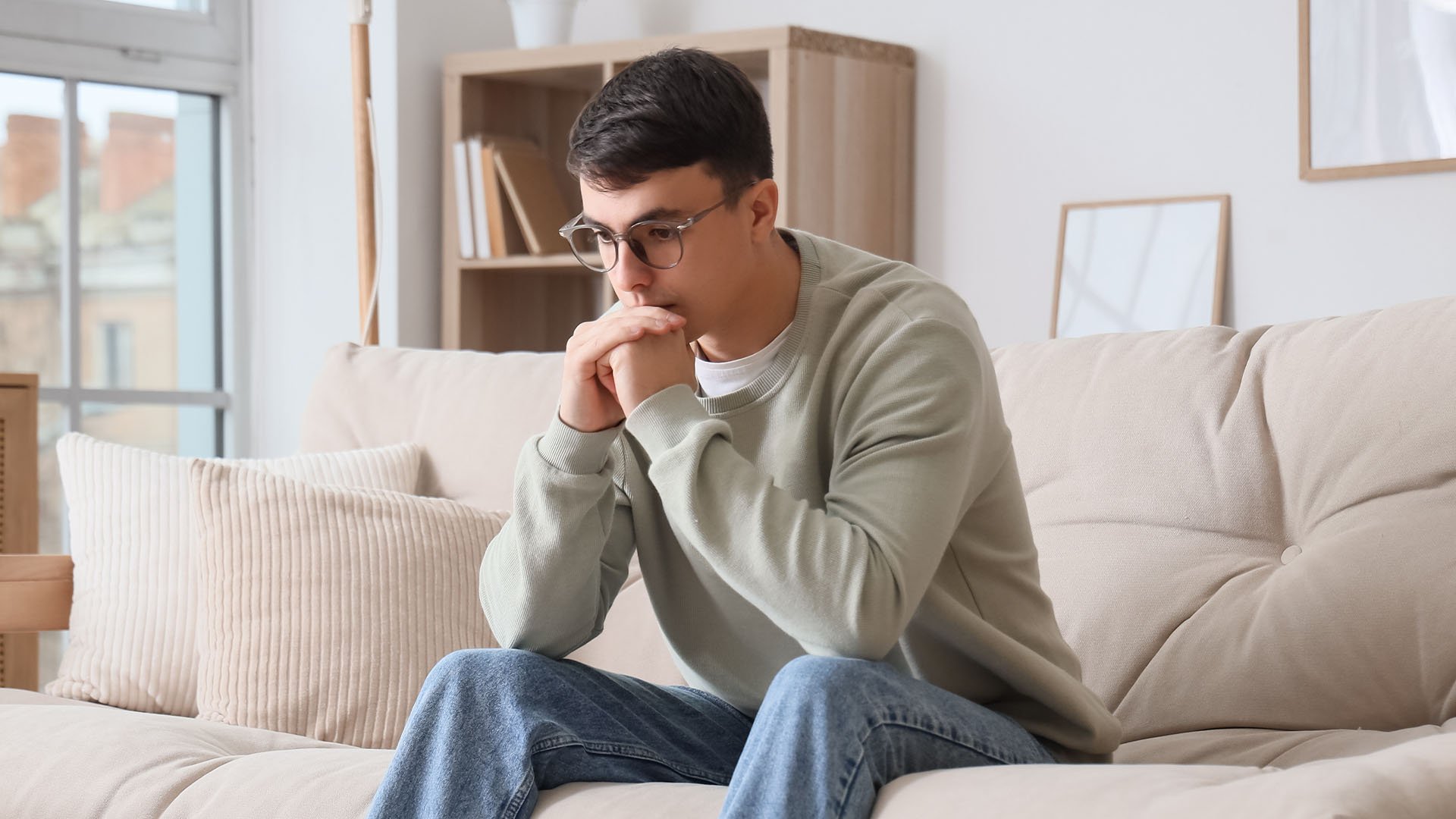 Un jóven pensativo en su sofá.