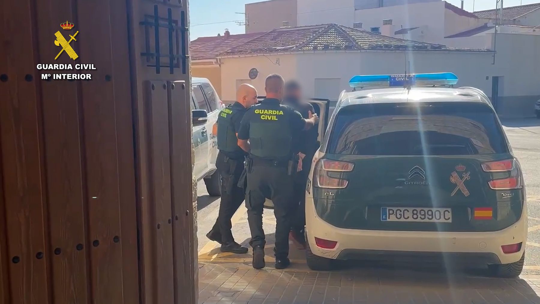 Agentes de la Guardia Civil con el detenido ante una puerta del vehículo.