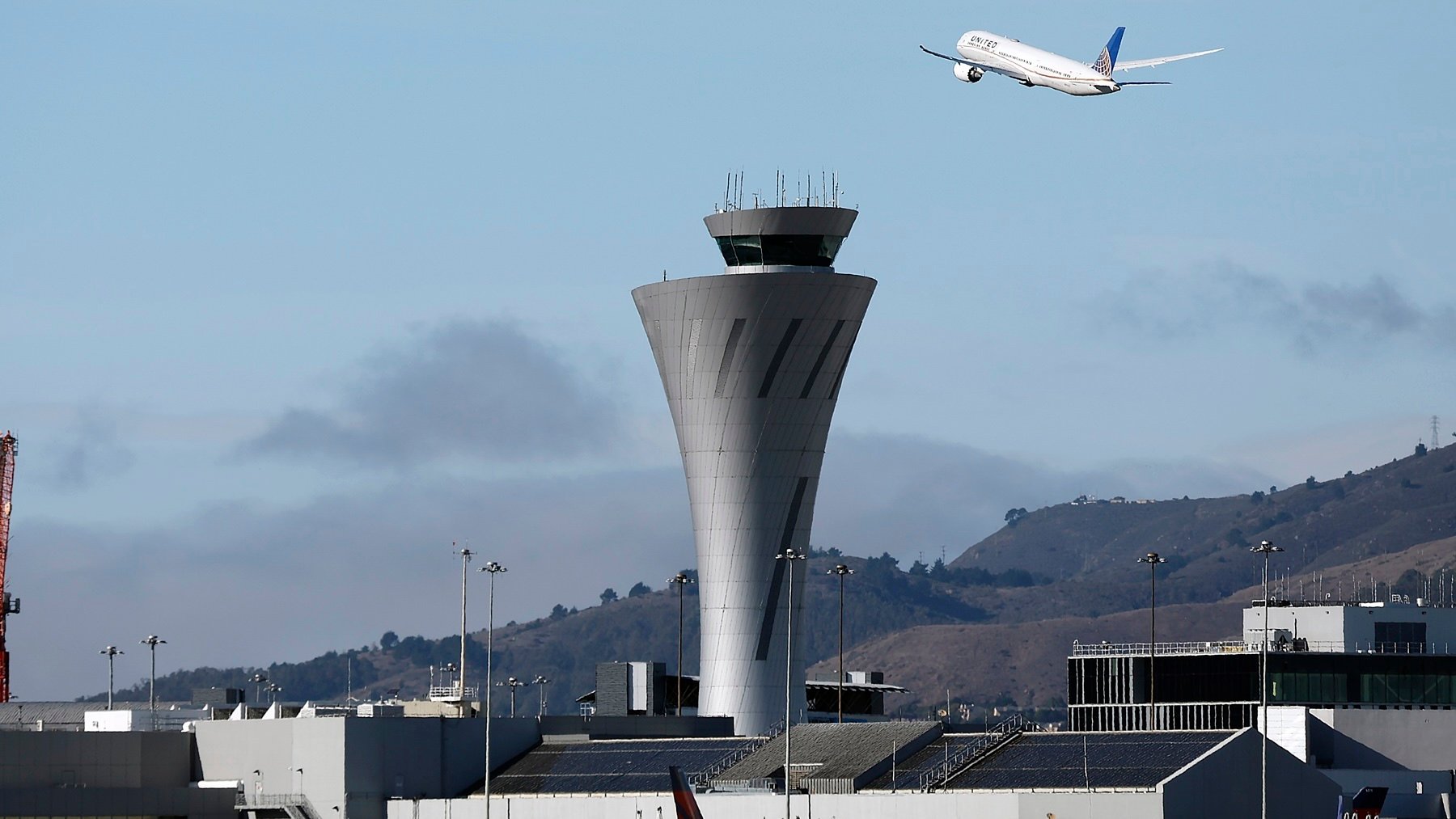 Un avión pasa tras la torre de control del aeropuerto de San Francisco. (EFE)