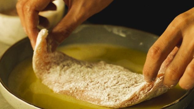 Pescado siendo empanado en huevo