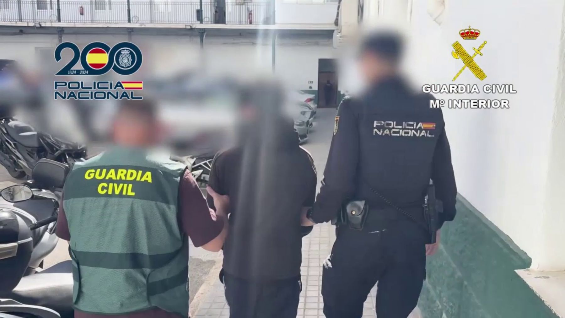 Uno de los detenidos es acompañado por un agente de la Guardia Civil y otro de la Policía Nacional.