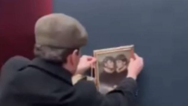 Un joven cuelga un cuadro en el Louvre