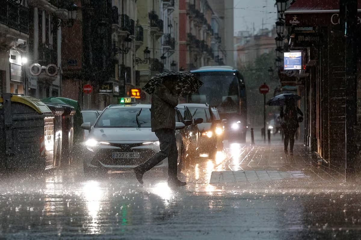 Hombre se protege con el paraguas bajo una tormenta con granizo.