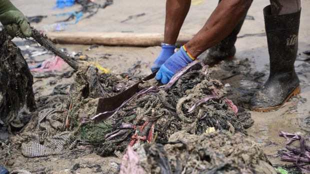 Retirada de residuos textiles con machetes en la playa de Accra