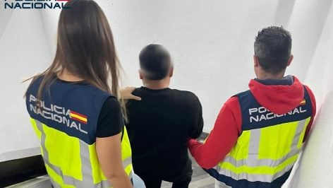 El detenido, de espaldas, custodiado por dos agentes de la Policía Nacional.