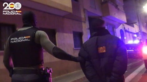 Un agente de la Policía Nacional con uno de los detenidos.