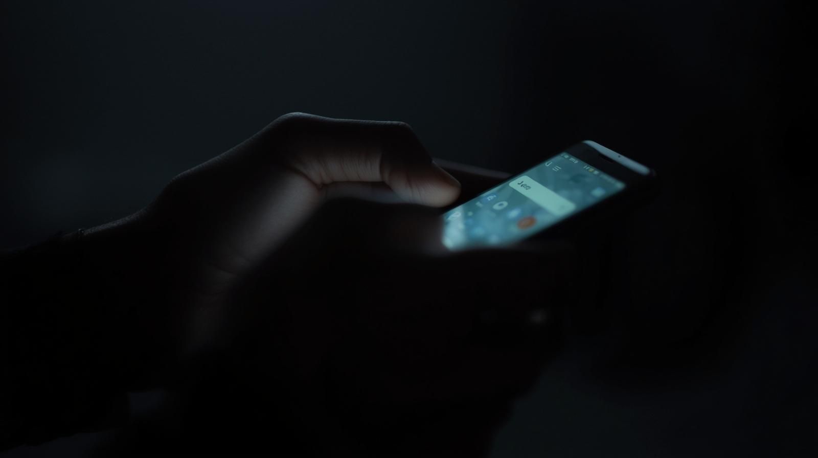 Manos sosteniendo un teléfono móvil iluminado, simbolizando la búsqueda online sobre amarres de amor.