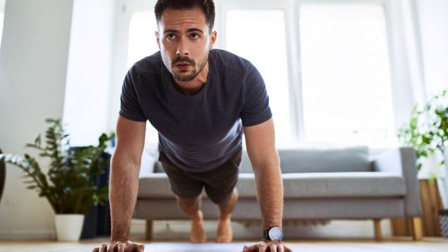 Un hombre hace deporte en casa.