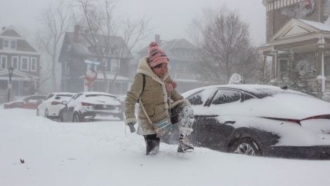 Mujer intenta caminar bajo una nevada de enormes dimensiones.