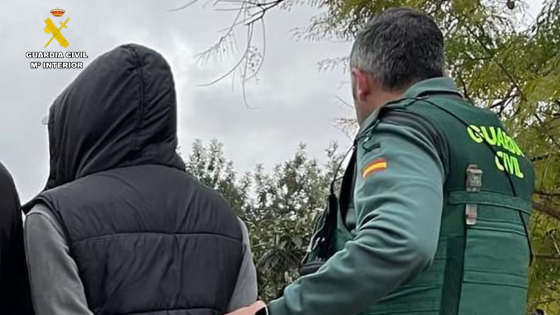 Un agente de la Guardia Civil acompaña a uno de los detenidos.