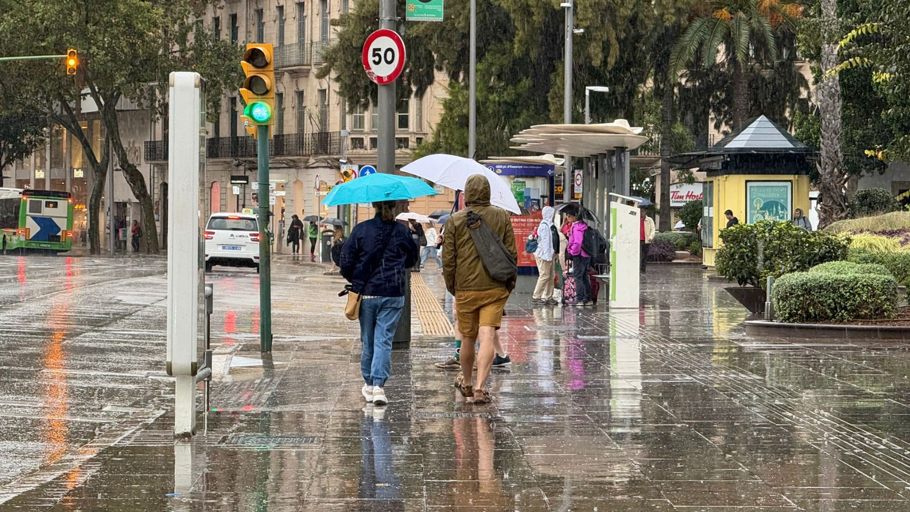 Viandantes protegiéndose de la lluvia en la plaza de España de Palma.