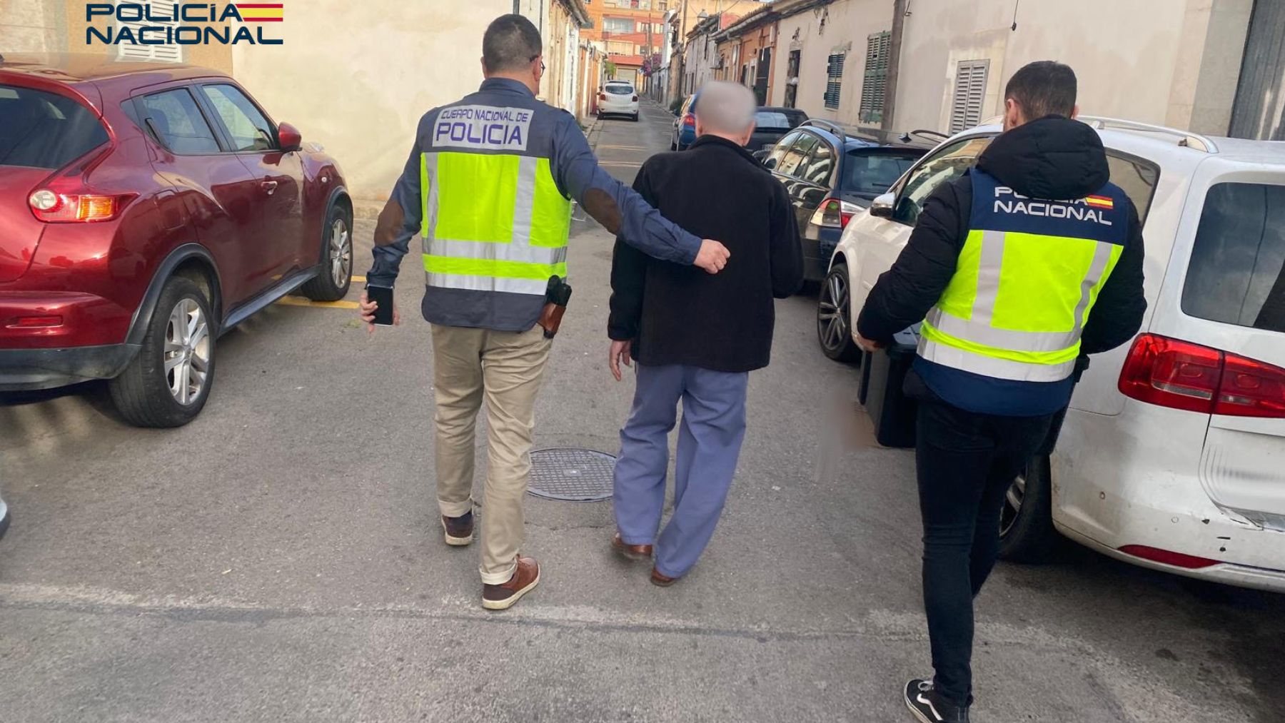 Dos policías nacionales custodiando al detenido tras registrar su domicilio.