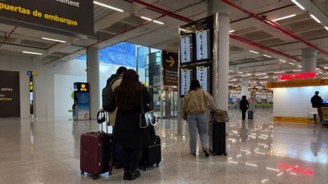 Pasajeros esperando para embarcar con chaquetones y bufandas.
