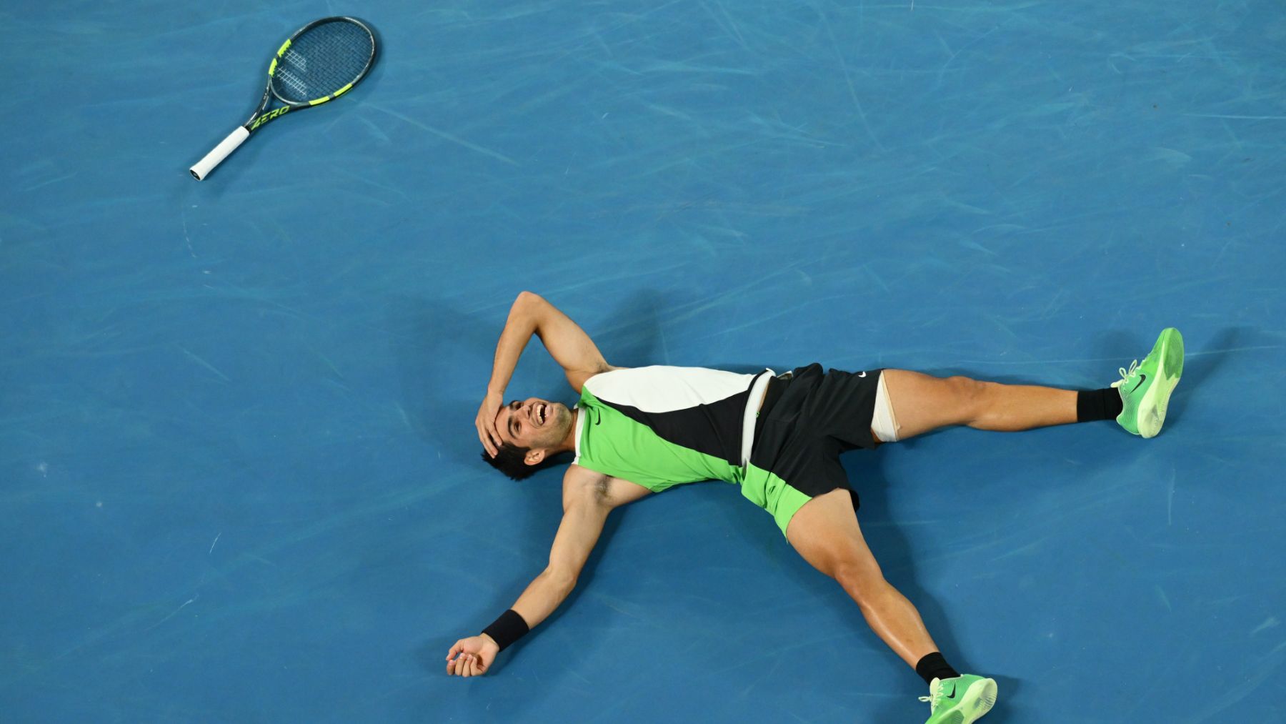Alcaraz sonríe en el suelo tras ganar el Open de Australia. (Getty)