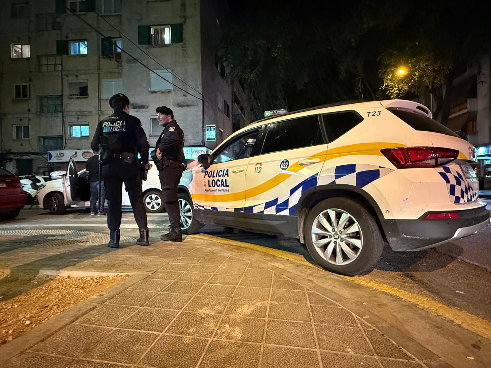 Dos agentes de la Policía Local de Palma junto al vehículo policial.