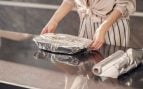 Mujer usando papel de aluminio para proteger alimentos en la cocina. (Foto: Freepik)