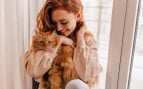 Joven mujer pelirroja con su gato naranja. Foto: Freepik