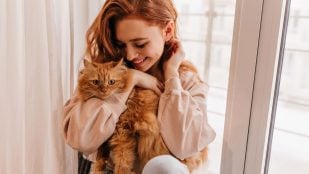 Joven mujer pelirroja con su gato naranja. Foto: Freepik