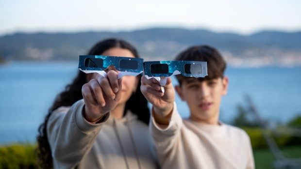 Foto: adolescentes mostrando gafas homologadas para ver eclipses. 