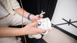 Daniel Honrales utiliza marcadores de seguimiento (los objetos en sus dedos y los que están adheridos a la taza) para capturar el movimiento en un teclado virtual. Foto: Universidad de Texas en Dallas