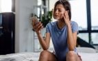 Una mujer utiliza el móvil con dolor de cabeza. Foto: Freepik