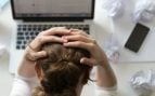 Persona estresada agarrándose la cabeza en el entorno laboral. Foto: Freepik