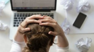Persona estresada agarrándose la cabeza en el entorno laboral. Foto: Freepik