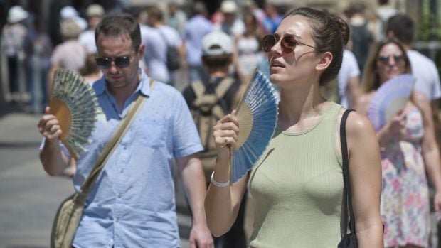 Gente abanic&aacute;ndose por el calor. Generado por IA.